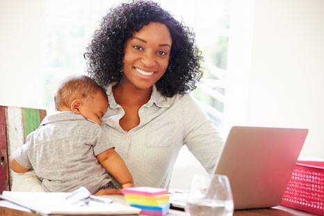 mom working while holding child